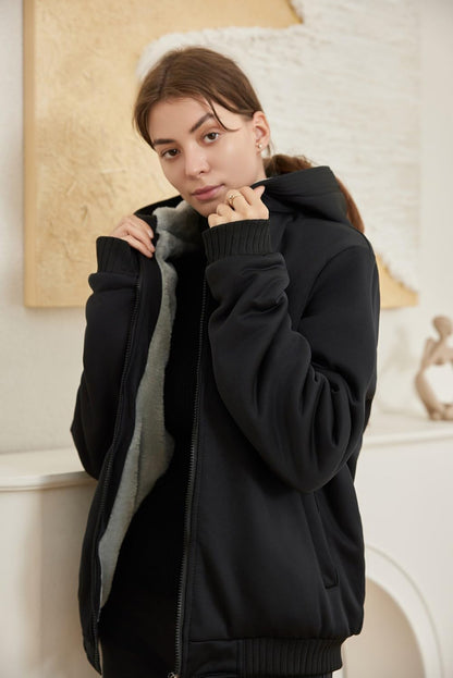 Frau in schwarzer Fleecejacke mit Kapuze, gemütlich, modisch, Winterkleidung, Innenaufnahme.