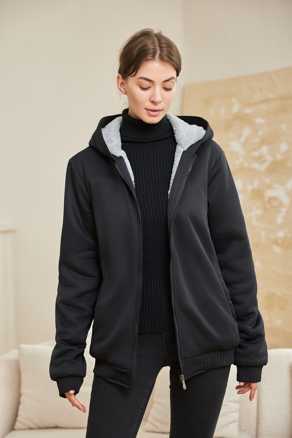 Frau in schwarzer Kapuzenjacke mit Fleece-Futter, modisch, warm, bequem, Winterkleidung.