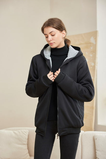 Frau in schwarzer Kapuzenjacke, Reißverschluss, Innenfutter grau, modisch, bequem, warm.