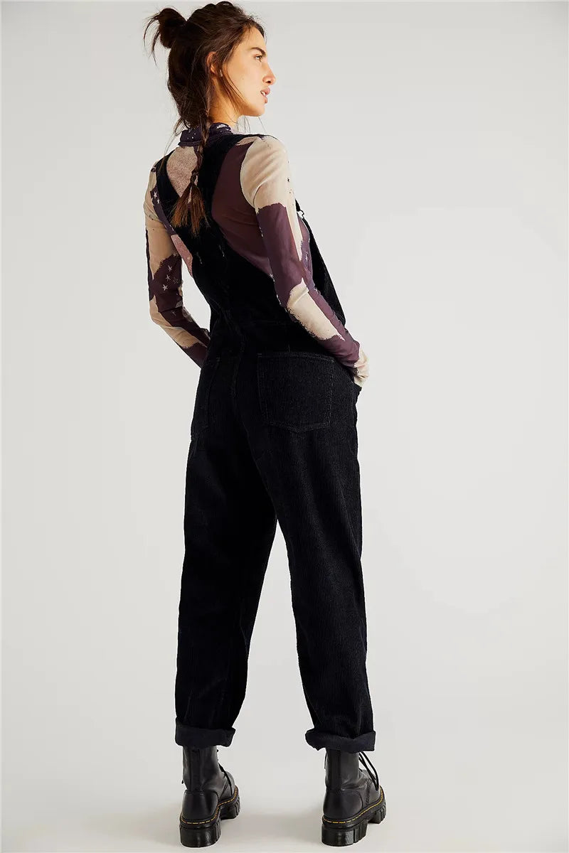 Frau in schwarzem Cord-Overall, Stiefel, gemustertes Langarmshirt, modisch, lässig