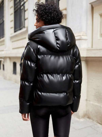 Frau in schwarzer, glänzender Daunenjacke auf städtischer Straße, Wintermode, Outdoor-Bekleidung.