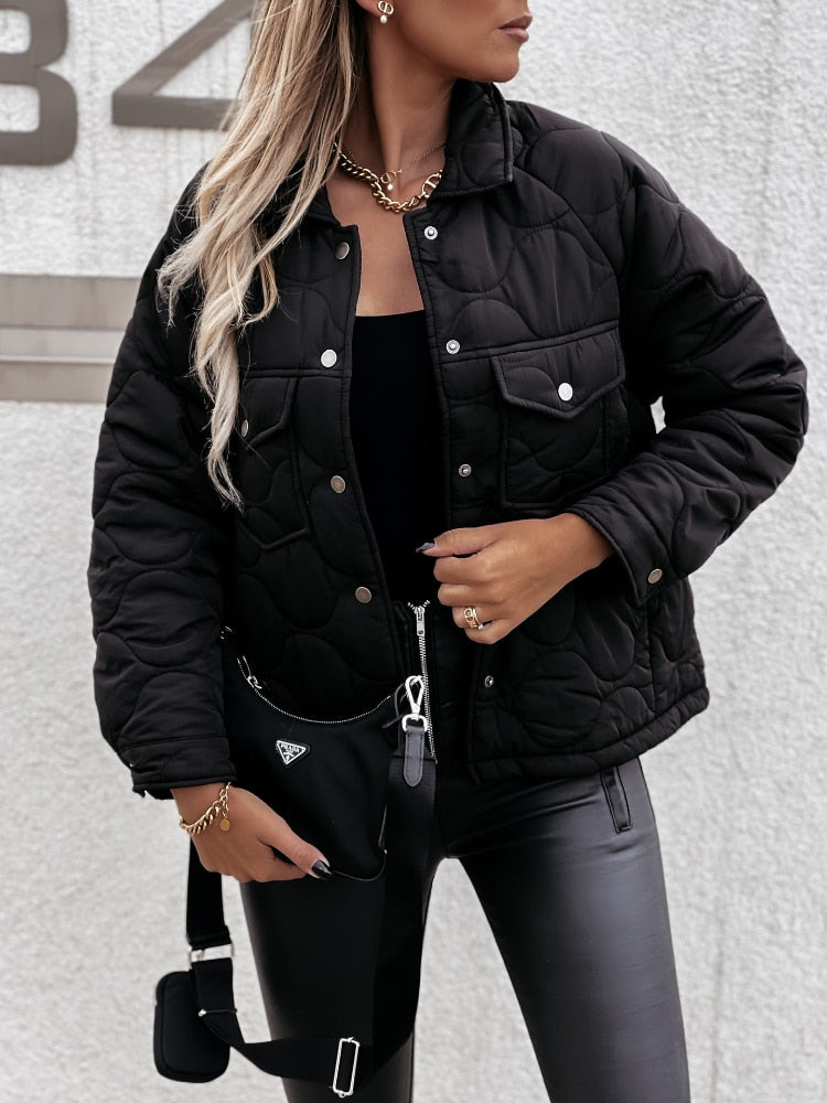 Frau in schwarzer Steppjacke, Lederhose, goldene Kette, modisch, urbaner Stil.