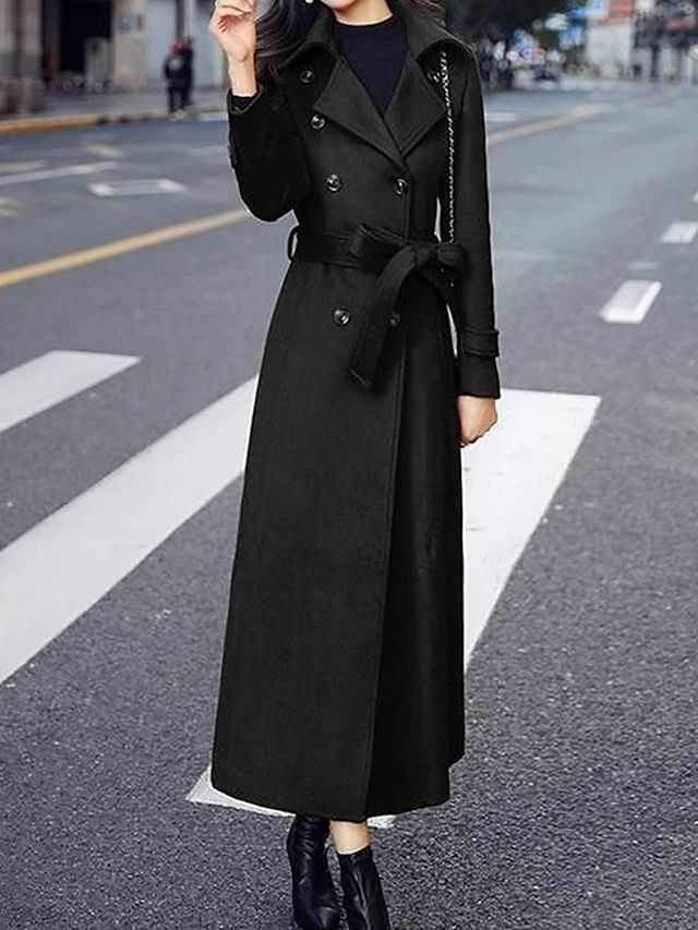 Frau in langem schwarzem Trenchcoat auf Straße, stilvolle Herbstmode, eleganter Mantel.