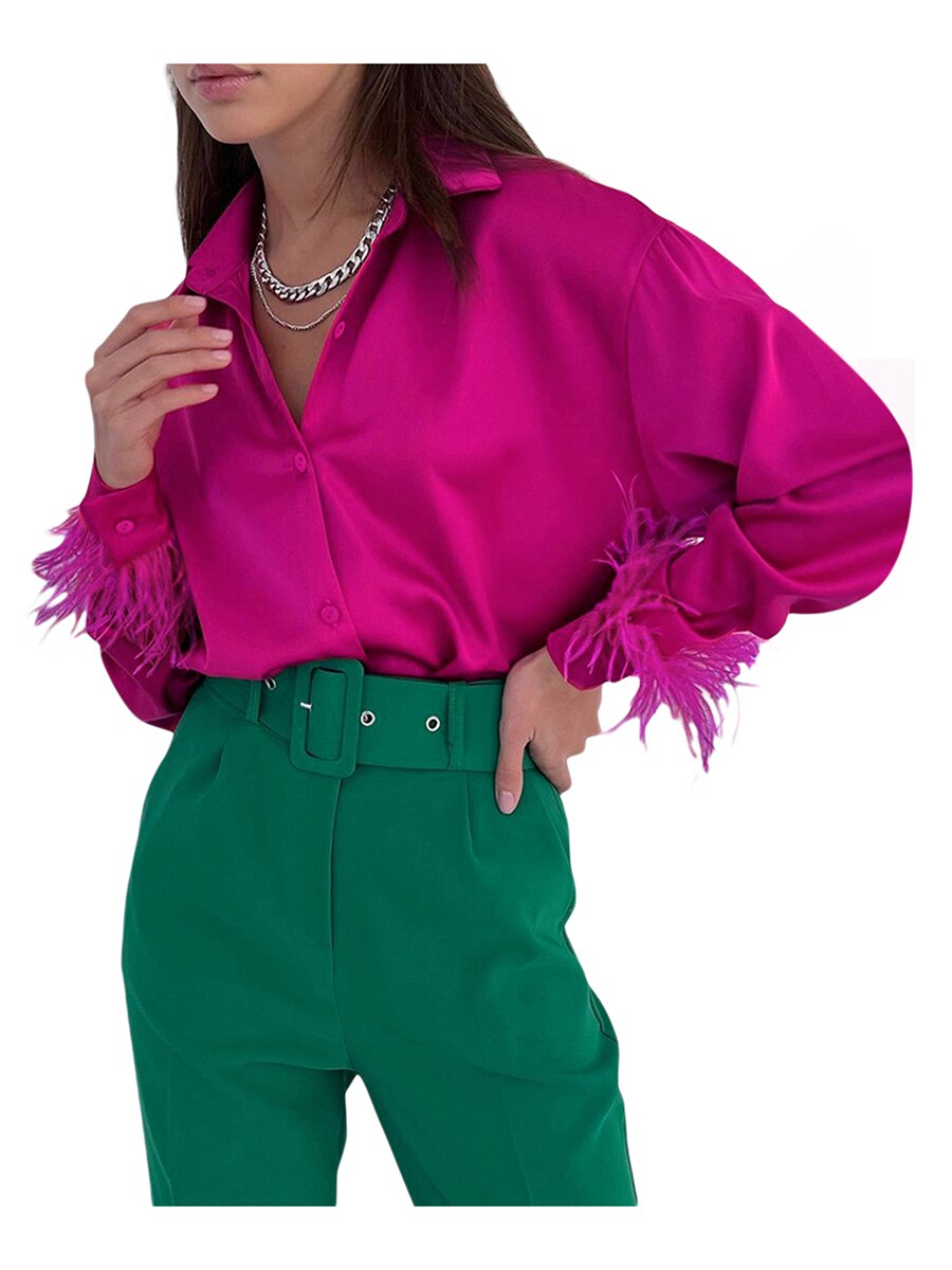 Frau in pinker Satinbluse mit Federn und grüner Hose, modisch, elegant, auffällige Kleidung.