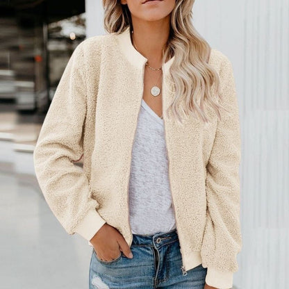 Frau in cremefarbener Teddyjacke, weißem T-Shirt und Jeans, lässiger Herbstlook.