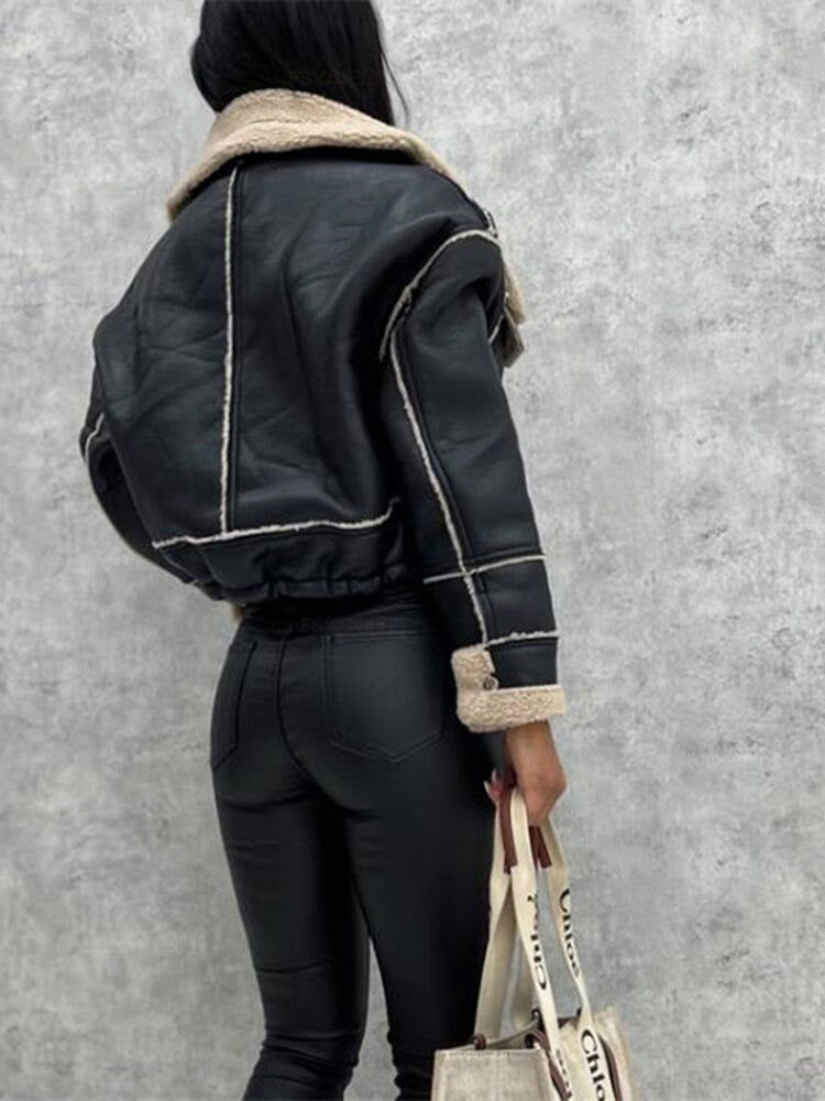 Frau in schwarzer Lederjacke mit Sherpa-Futter, hält eine Tasche, modisch, warm, Herbstkleidung.