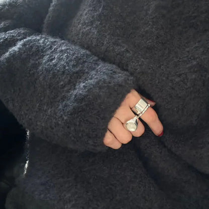 Dunkelgrauer Wollpullover, Hand mit silbernen Ringen, modisches Accessoire, Winterkleidung.