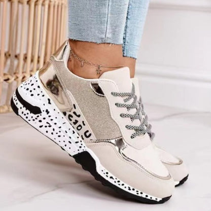 Beige Damen-Sneaker mit Metallic-Details, gepunkteter Sohle und Schnürsenkeln, modisch und bequem.
