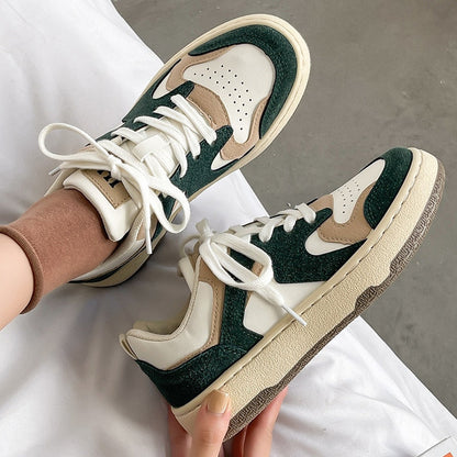 Grüne und weiße Sneaker aus Leder, sportlich, modisch, Damen, auf grauem Hintergrund.