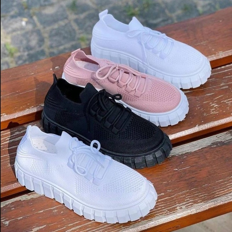 Drei Paar Sneaker auf Bank, weiß, rosa, schwarz, atmungsaktives Mesh, modische Freizeitschuhe.