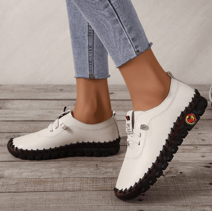Weiße Damen-Sneaker aus Leder, schwarze Sohle, lässig, bequem, modisch, Jeans-Hintergrund.