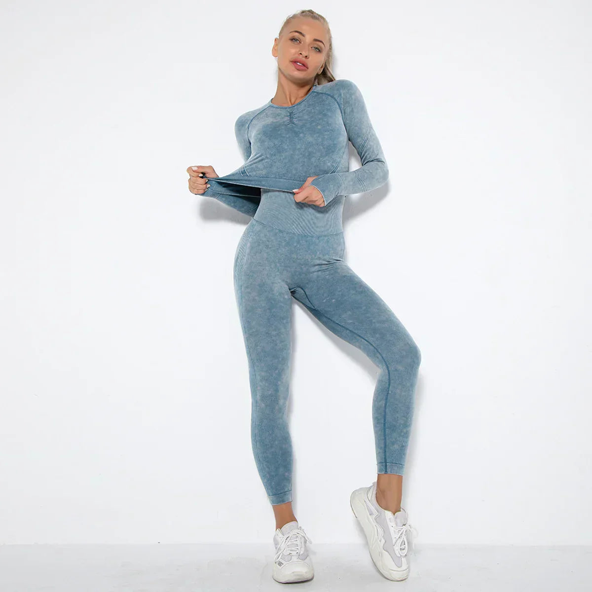 Frau in blauem nahtlosem Sportanzug, Langarm, Leggings, Fitnessmode, vor weißem Hintergrund.