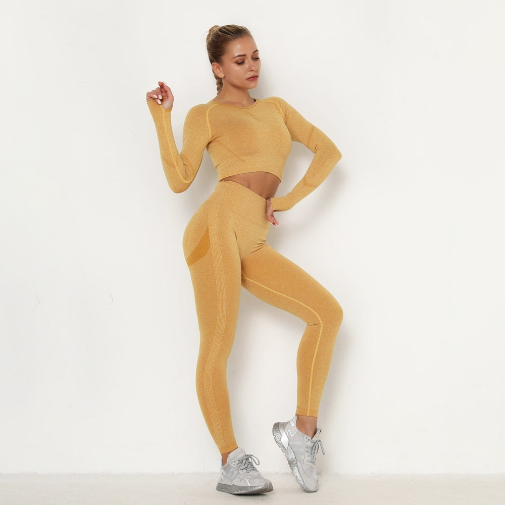 Frau in gelbem nahtlosem Sport-Set, Langarm-Top und Leggings, graue Turnschuhe.