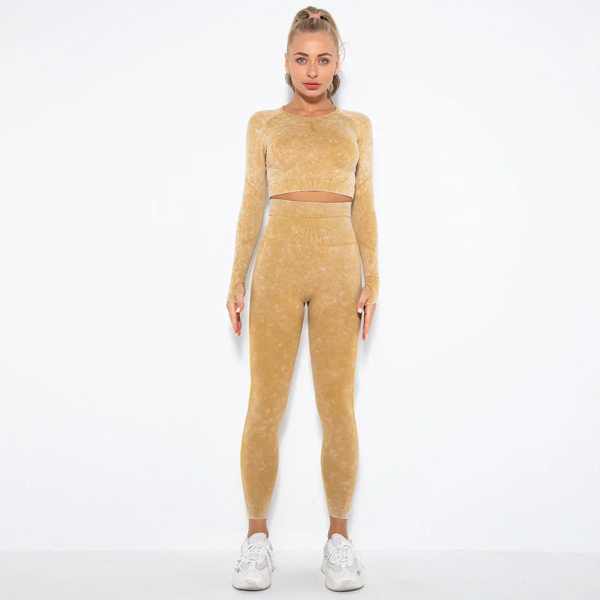 Frau in gelbem Sportanzug, nahtlos, langärmelig, mit Leggings, vor weißem Hintergrund.