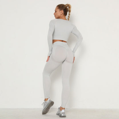 Frau in grauem Sport-Set, langärmeliges Oberteil und Leggings, Fitnessmode, Rückansicht.