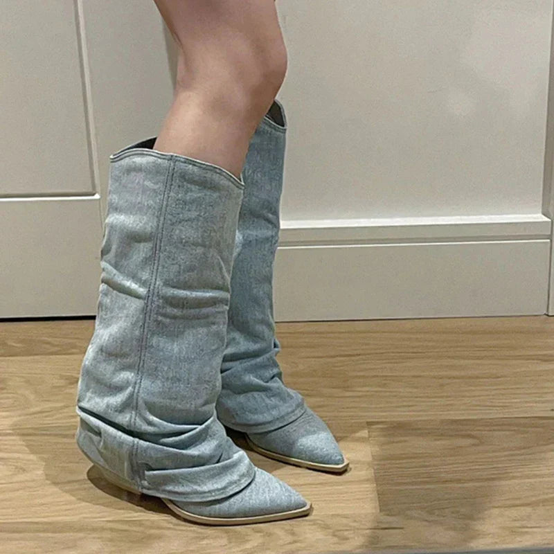 Damen Stiefel aus hellblauem Denim, kniehoch, spitz zulaufend, modisch, auf Holzboden.