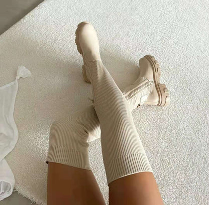 Beige kniehohe Stiefel mit dicker Sohle auf Teppich, modisch, Damenmode, Herbsttrends.