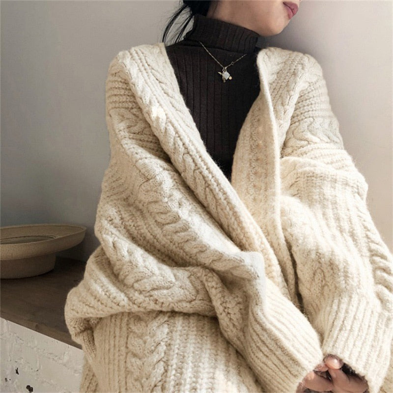 Frau trägt cremefarbenen Strickpullover, Zopfmuster, gemütlich, modisch, Herbst-Winter-Look.