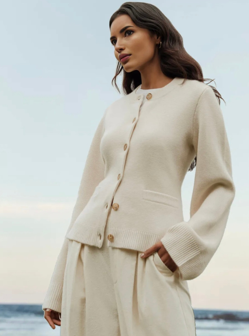 Frau in cremefarbenem Strick-Cardigan am Strand, elegantes Herbst-Outfit, Damenmode.