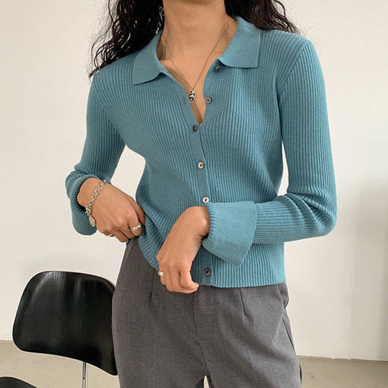 Frau trägt blauen Strick-Cardigan mit Knöpfen, graue Hose, modisch, elegant, Herbstmode.