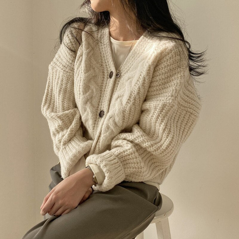 Frau trägt cremeweißen Strickcardigan, Zopfmuster, lässig, gemütlich, Herbstmode.