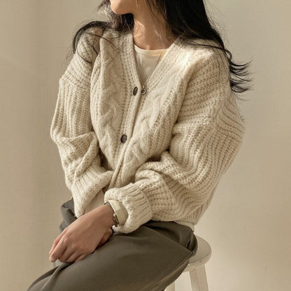 Frau trägt cremeweißen Strickcardigan, Zopfmuster, lässig, gemütlich, Herbstmode.