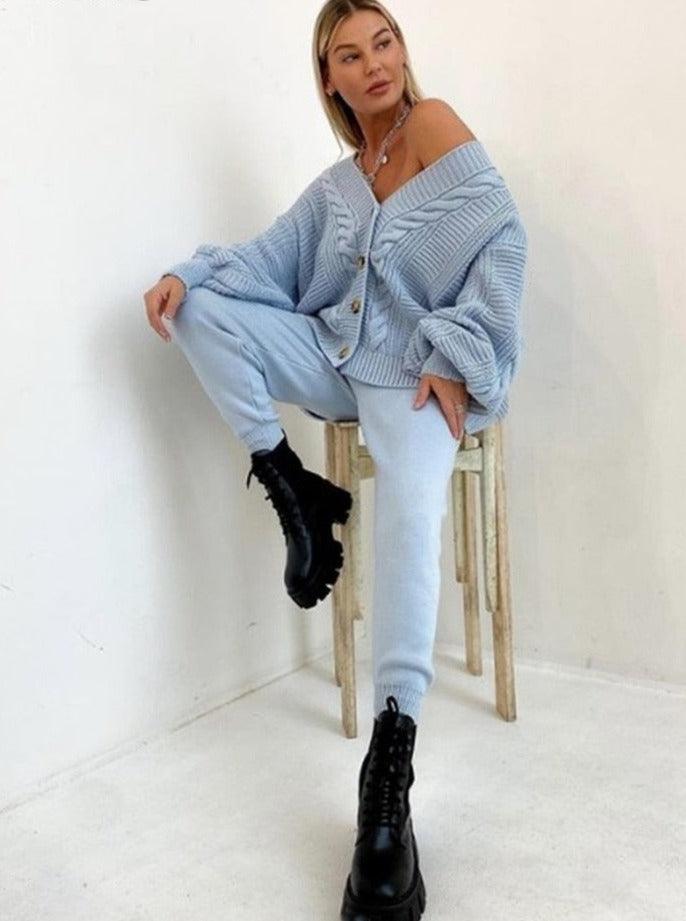 Frau in hellblauem Strickpullover und Jogginghose, schwarze Stiefel, lässige Mode.