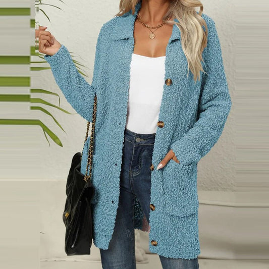 Frau trägt hellblauen Strickmantel, weiße Bluse, Jeans, goldene Kette, schwarze Tasche.