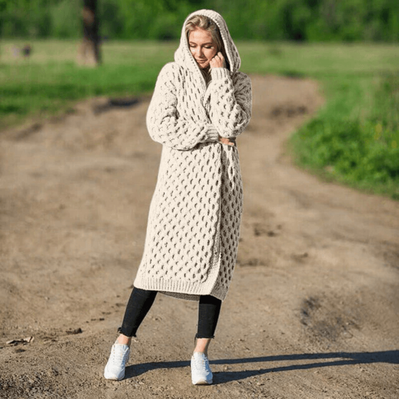 Frau in beigem Strickmantel mit Kapuze, lässig, übergroß, Herbstmode, draußen.