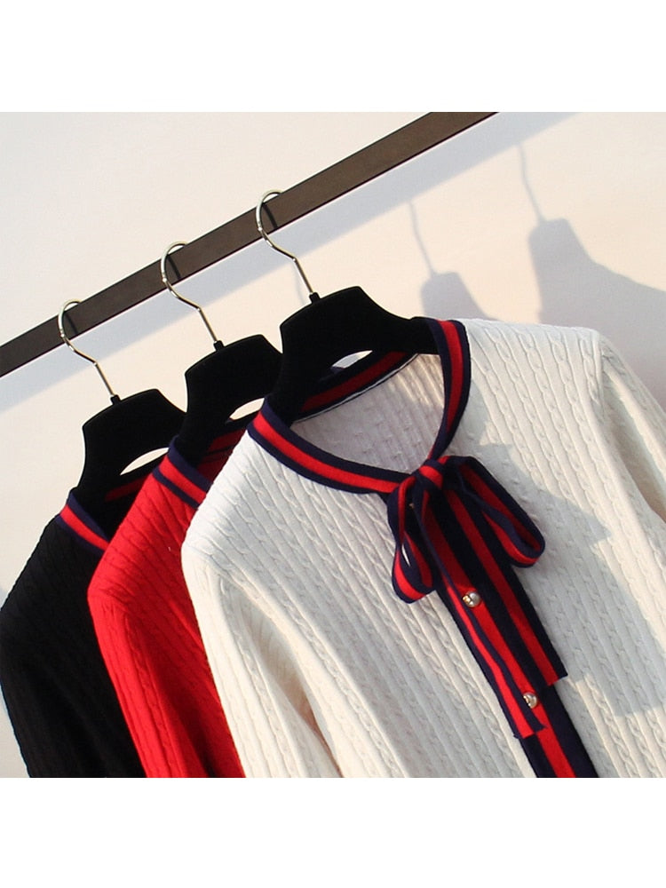 Drei Strickjacken mit Schleife, schwarz, rot, weiß, auf Kleiderbügeln, Damenmode, elegant.