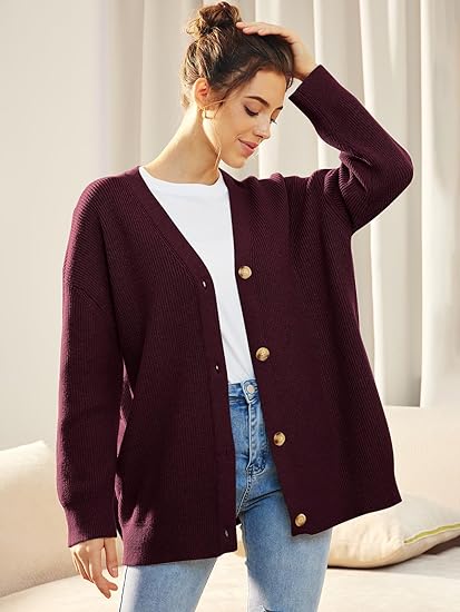 Frau trägt lila Strickjacke mit Knöpfen, weißes T-Shirt, blaue Jeans, lässiger Look.