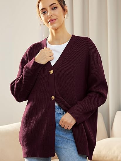 Frau trägt lila Strickjacke mit Knöpfen, weißes T-Shirt, blaue Jeans, gemütlicher Look.