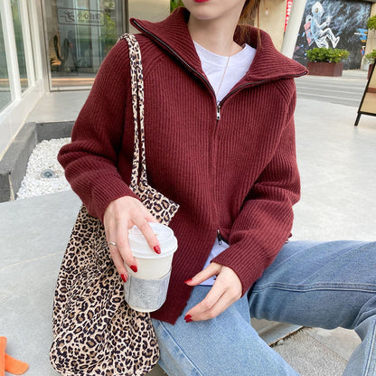 Frau in bordeauxrotem Strickpullover mit Reißverschluss, Leopardenmuster-Tasche, Kaffeebecher.