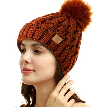 Frau mit brauner Strickmütze, Bommel, Wintermode, Damenaccessoire, warm, stilvoll.