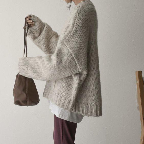 Frau in beigem Strickpullover mit brauner Tasche, lässiger Herbstlook, gemütliche Mode.