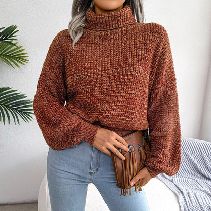 Frau in braunem Strickpullover mit Rollkragen, blaue Jeans, braune Fransenhandtasche.