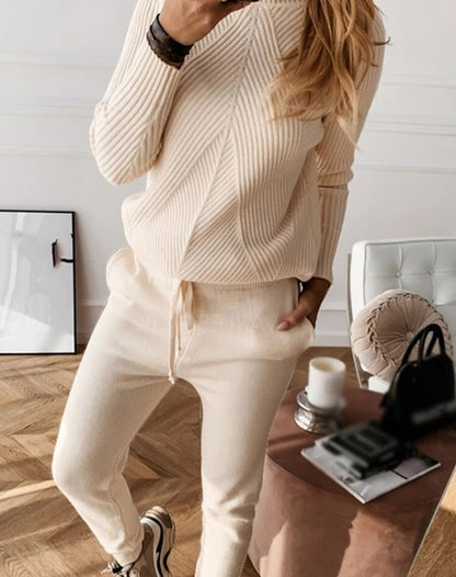 Frau in cremefarbenem Strickpullover und Jogginghose, gemütliches Wohnzimmer, Mode, Herbst.