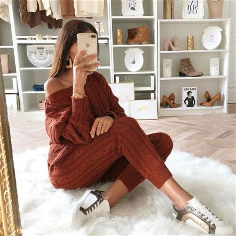 Frau in braunem Strickpullover und Hose, Selfie, modische Sneakers, gemütliches Wohnzimmer.