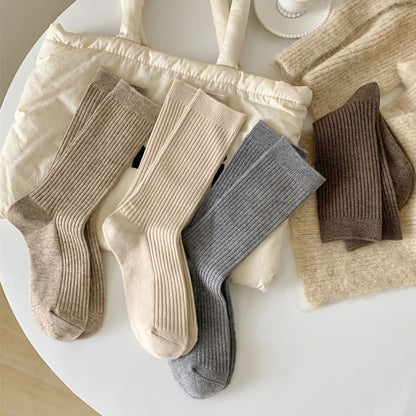 Vier Paar gerippte Socken in Beige, Creme, Grau und Braun auf weißem Tisch.