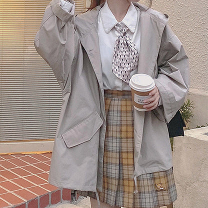 Damenmode: Beige Trenchcoat, kariertes Rock, weiße Bluse, Kaffeebecher, Herbstoutfit.