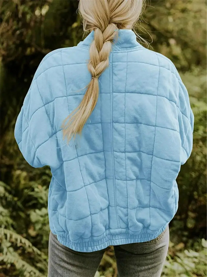 Frau in blauer, gesteppten Übergangsjacke, oversized, draußen im Grünen.