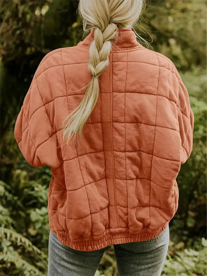 Frau in orangefarbener, gesteppter Übergangsjacke im Wald, Herbstmode Damen.
