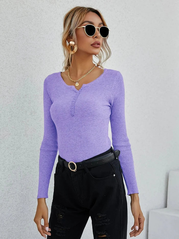 Frau in lila V-Ausschnitt-Pullover, schwarze Hose, Sonnenbrille, modisch, elegant.