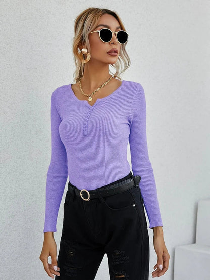 Frau in lila V-Ausschnitt-Pullover, schwarze Hose, Sonnenbrille, modisch, elegant.