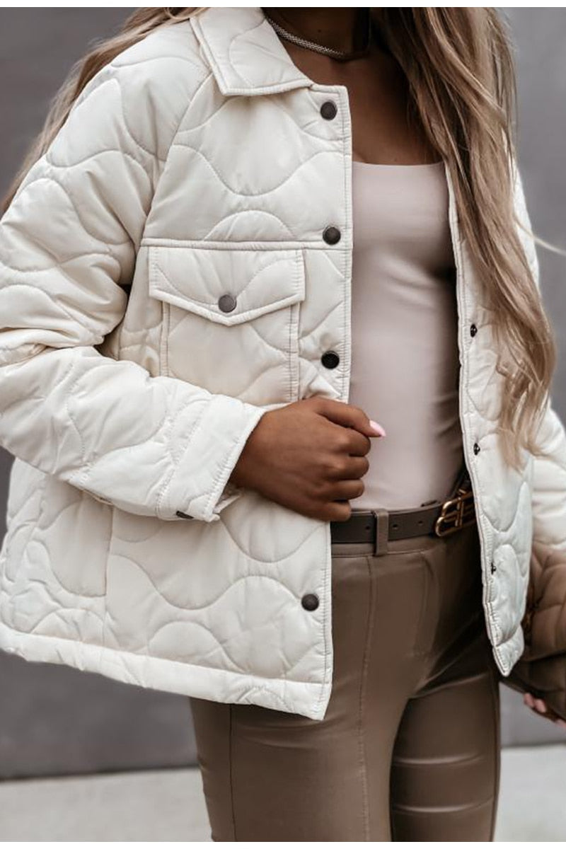 Frau in cremefarbener Steppjacke, beige Top, braune Hose, modisch, Herbstmode.