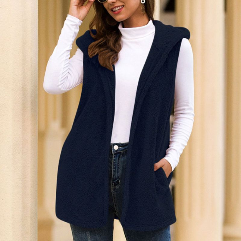 Frau trägt dunkelblaue ärmellose Weste, weißes Langarmshirt, lässiger Herbstlook.