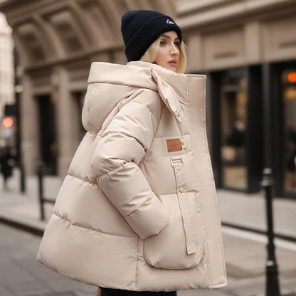 Frau in beiger Winterjacke mit Kapuze, warm, winddicht, modisch, auf städtischer Straße.