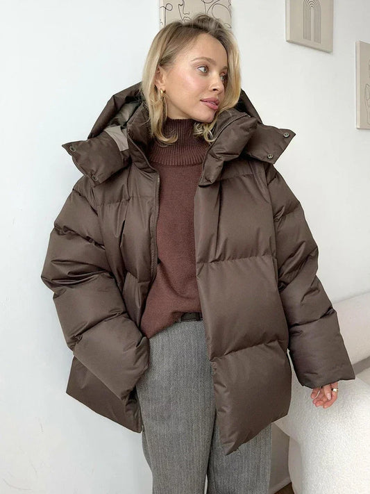 Frau in brauner Daunenjacke, Rollkragenpullover, graue Hose, Wintermode, gemütlich, stilvoll.