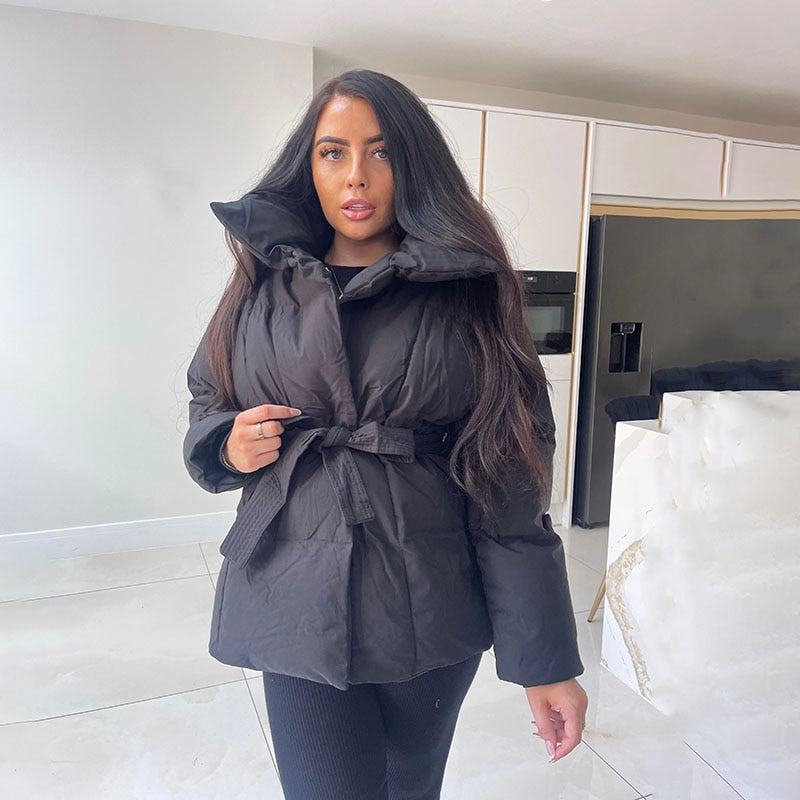 Frau in schwarzer Daunenjacke mit Gürtel, Wintermode, Indoor-Aufnahme.