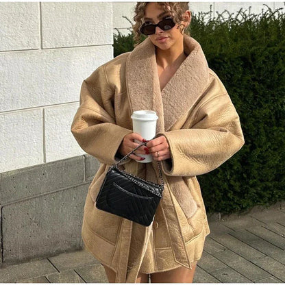 Frau in beigem Oversize-Mantel mit schwarzer Tasche und Kaffeebecher, modisch, urbaner Stil.